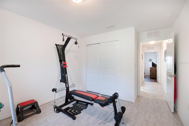 workout room with a textured ceiling and light hardwood / wood-style flooring