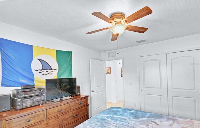 bedroom with ceiling fan, a textured ceiling, and a closet