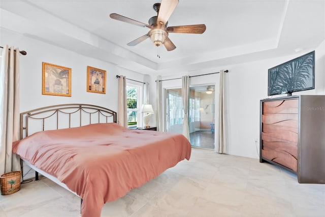 bedroom with access to exterior, a raised ceiling, and ceiling fan