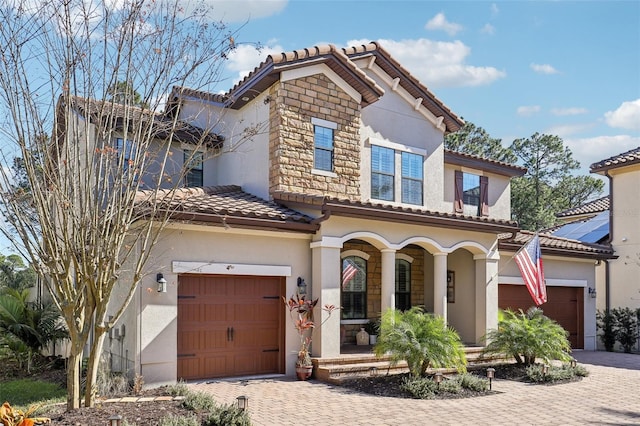 mediterranean / spanish home with stucco siding, driveway, covered porch, an attached garage, and a tiled roof