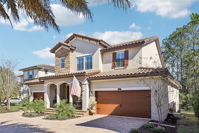 mediterranean / spanish house with stucco siding, decorative driveway, and a tiled roof