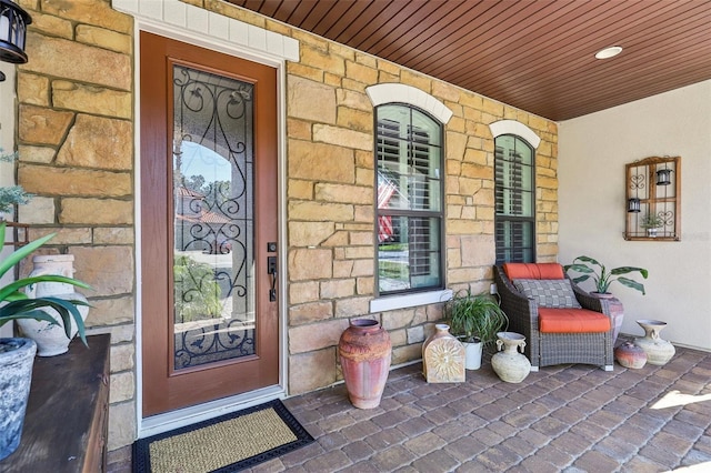 doorway to property with stone siding and a porch