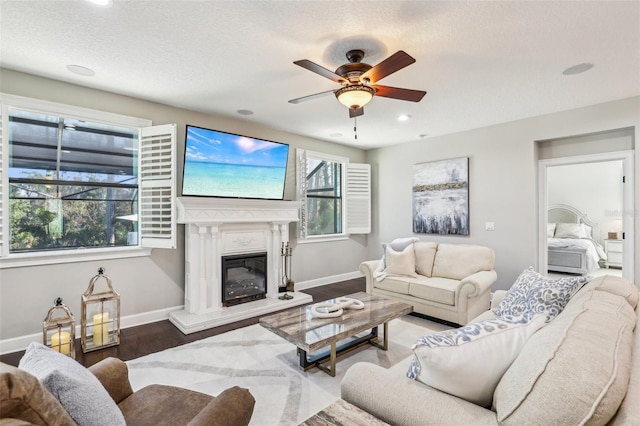 living room with hardwood / wood-style flooring, ceiling fan, and a textured ceiling