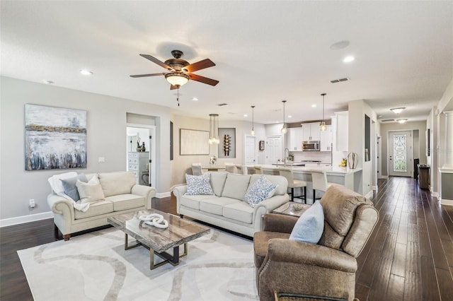 living room with dark hardwood / wood-style flooring, sink, and ceiling fan