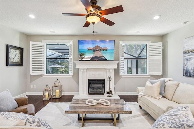 living room with hardwood / wood-style flooring, ceiling fan, and a textured ceiling