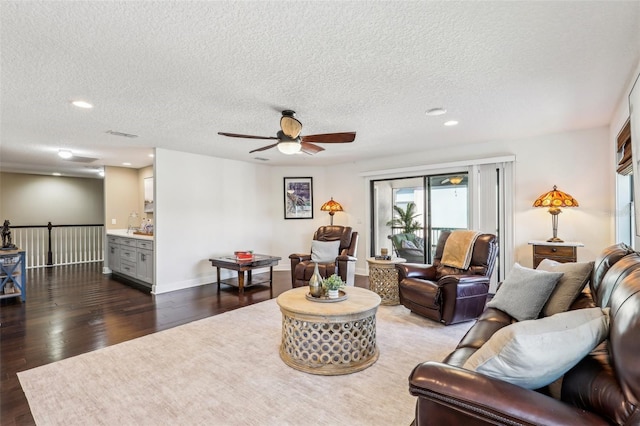 living room with ceiling fan, dark wood-type flooring, and a textured ceiling