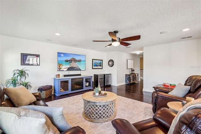 living room with dark hardwood / wood-style floors, a textured ceiling, and ceiling fan