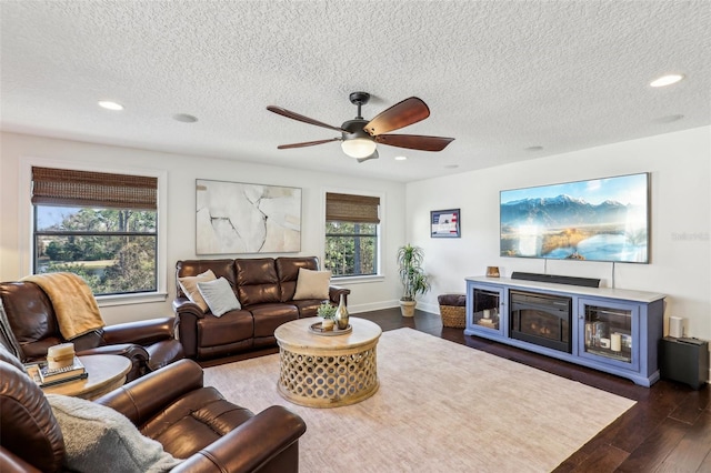 living room featuring dark hardwood / wood-style floors, a textured ceiling, a fireplace, and ceiling fan