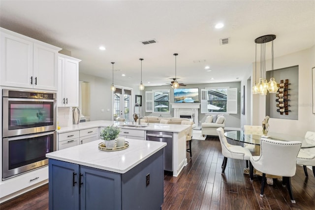 kitchen with appliances with stainless steel finishes, sink, hanging light fixtures, and white cabinets