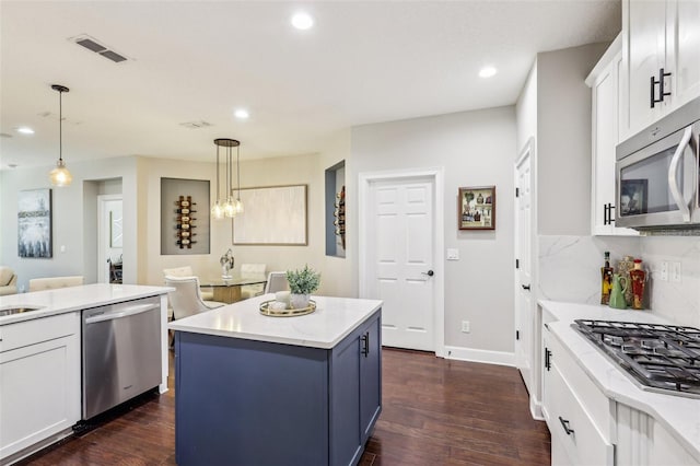 kitchen with white cabinetry, a center island, dark hardwood / wood-style floors, pendant lighting, and stainless steel appliances