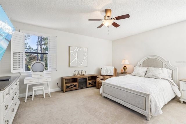 bedroom featuring light carpet, baseboards, a textured ceiling, and ceiling fan