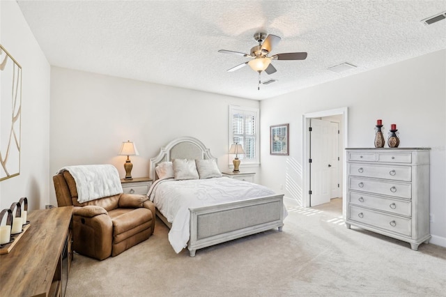 bedroom with ceiling fan, light colored carpet, and a textured ceiling