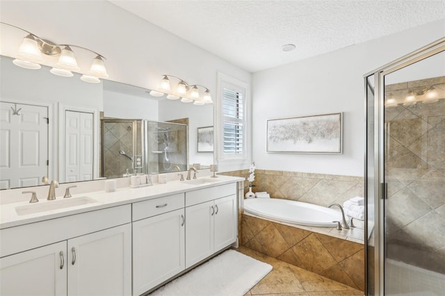 bathroom featuring a textured ceiling, a shower stall, double vanity, and a sink