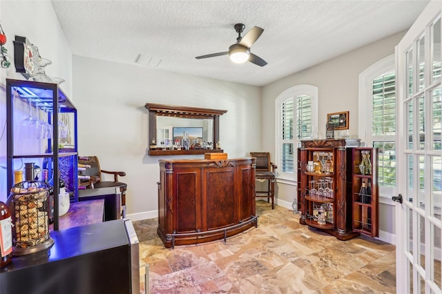 home office with a textured ceiling, ceiling fan, and french doors