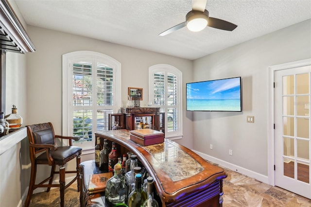 office space featuring baseboards, a healthy amount of sunlight, a textured ceiling, and ceiling fan