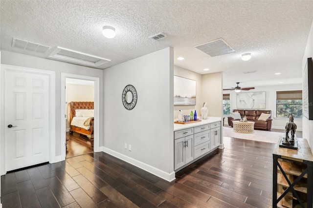 interior space featuring ceiling fan, dark wood-type flooring, and a textured ceiling