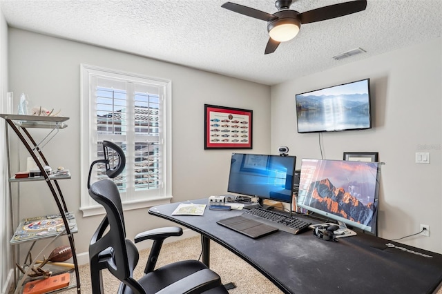 carpeted office space featuring ceiling fan and a textured ceiling