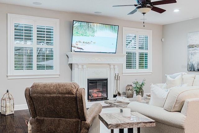 living room featuring baseboards, dark wood finished floors, recessed lighting, a glass covered fireplace, and a ceiling fan