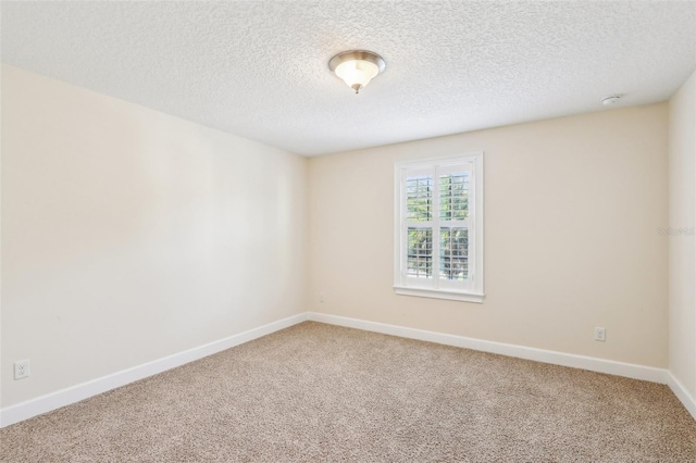 empty room featuring baseboards, light colored carpet, and a textured ceiling