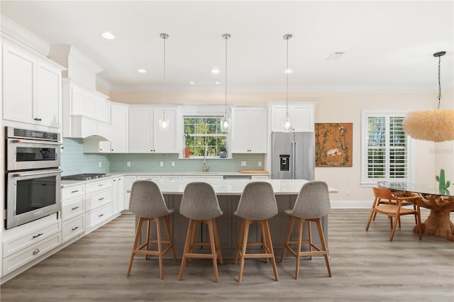 kitchen with a kitchen island, white cabinetry, appliances with stainless steel finishes, and hanging light fixtures