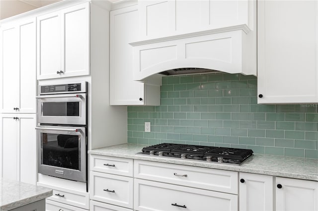 kitchen featuring backsplash, appliances with stainless steel finishes, custom exhaust hood, and white cabinets