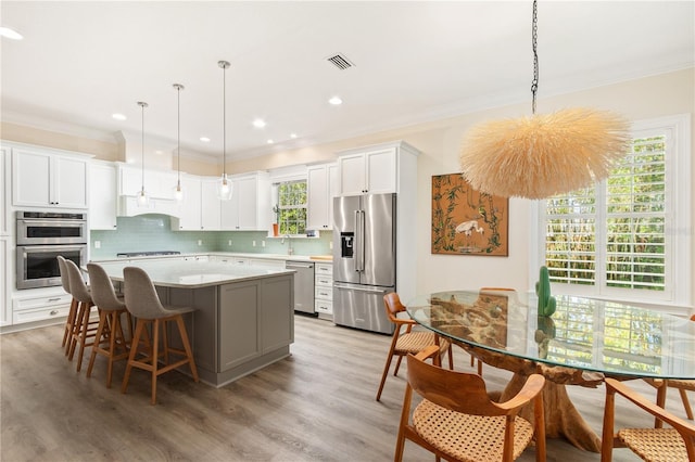 kitchen featuring hanging light fixtures, stainless steel appliances, white cabinets, and a kitchen island