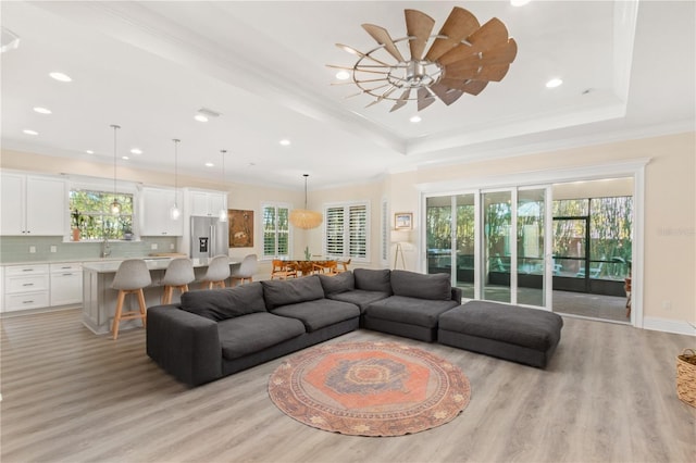 living room with crown molding, plenty of natural light, and a tray ceiling