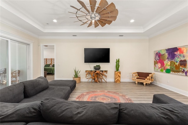 living room with a tray ceiling, ornamental molding, light hardwood / wood-style floors, and ceiling fan