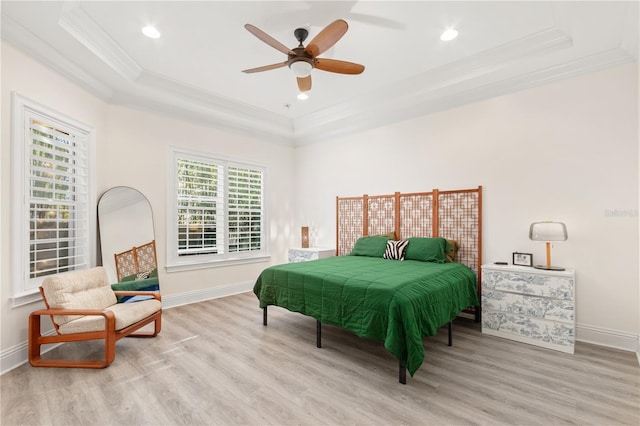 bedroom with ceiling fan, ornamental molding, a tray ceiling, and light wood-type flooring