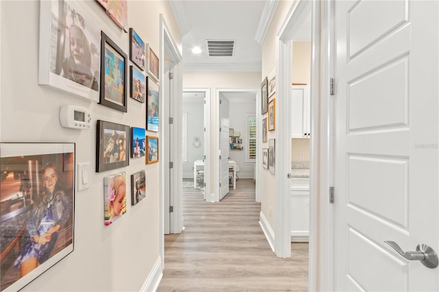 hallway with crown molding and light wood-type flooring