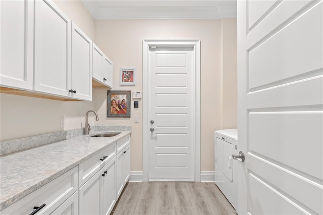 clothes washing area featuring sink, light hardwood / wood-style flooring, cabinets, independent washer and dryer, and ornamental molding