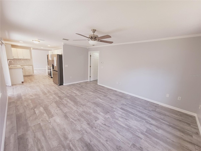 unfurnished living room with sink, crown molding, ceiling fan, and light wood-type flooring