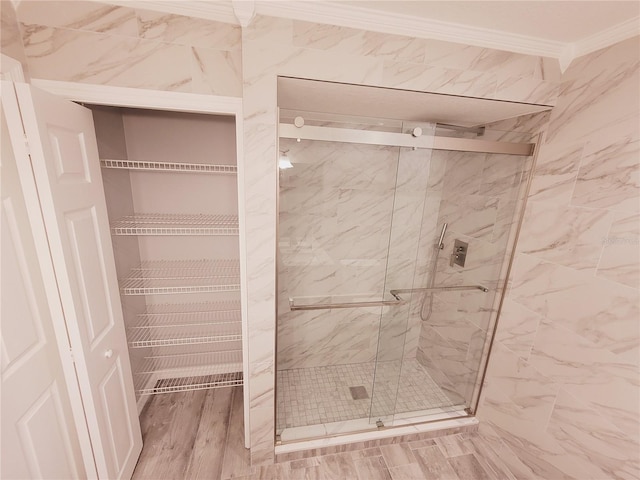 bathroom with wood-type flooring, ornamental molding, and walk in shower