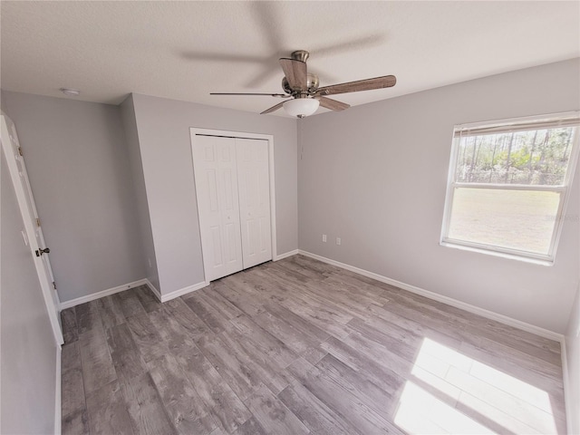 unfurnished bedroom featuring a textured ceiling, light hardwood / wood-style flooring, a closet, and ceiling fan