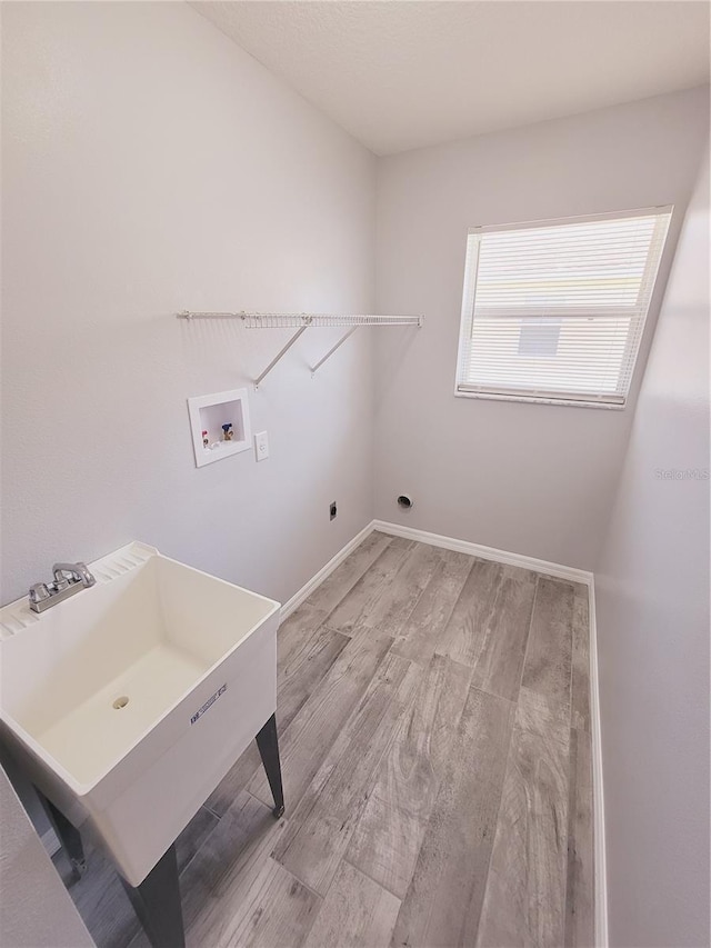 laundry area with sink, hookup for a washing machine, light hardwood / wood-style floors, and hookup for an electric dryer