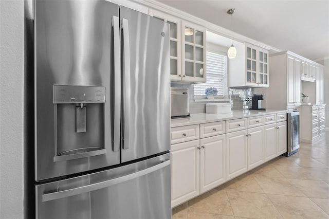 kitchen with hanging light fixtures, stainless steel fridge, white cabinets, and light tile patterned flooring