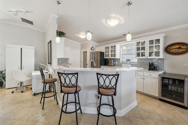 kitchen featuring a breakfast bar, white cabinetry, stainless steel fridge, pendant lighting, and beverage cooler