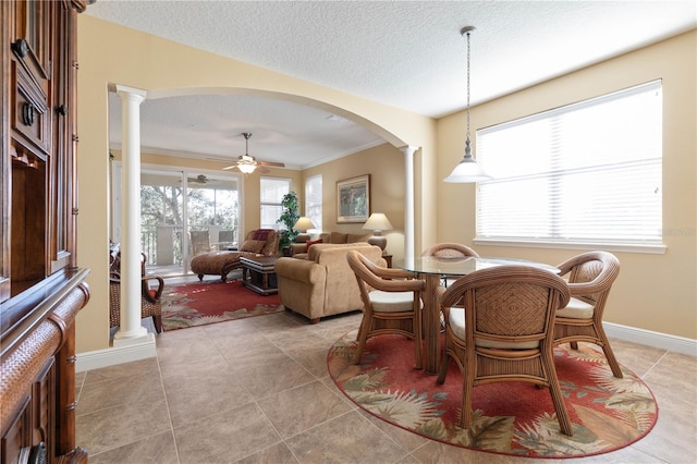 dining room with light tile patterned flooring, ornate columns, crown molding, a textured ceiling, and ceiling fan