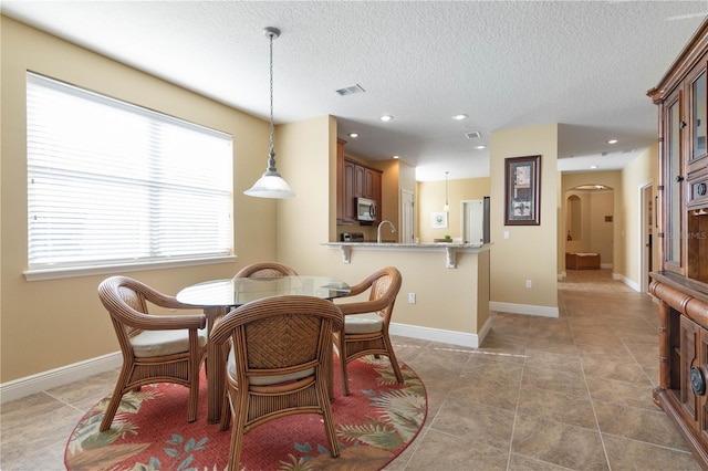 dining space with light tile patterned flooring, sink, and a textured ceiling