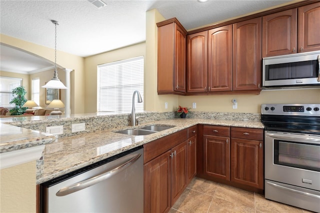 kitchen with appliances with stainless steel finishes, pendant lighting, sink, light stone counters, and a textured ceiling