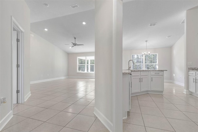 interior space with light tile patterned flooring, lofted ceiling, sink, and ceiling fan with notable chandelier