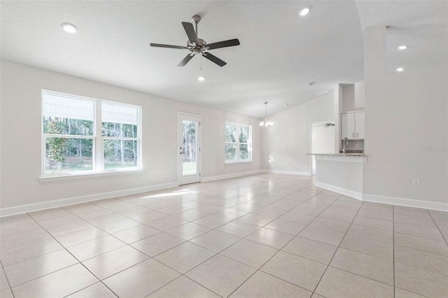 unfurnished living room with light tile patterned flooring, lofted ceiling, sink, and ceiling fan with notable chandelier