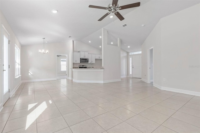 unfurnished living room with light tile patterned flooring, ceiling fan with notable chandelier, and high vaulted ceiling