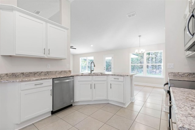 kitchen with decorative light fixtures, stainless steel appliances, white cabinets, and light tile patterned flooring