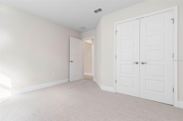 unfurnished bedroom with light colored carpet and a closet