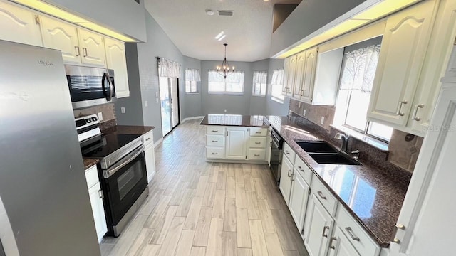 kitchen with sink, a chandelier, hanging light fixtures, appliances with stainless steel finishes, and kitchen peninsula