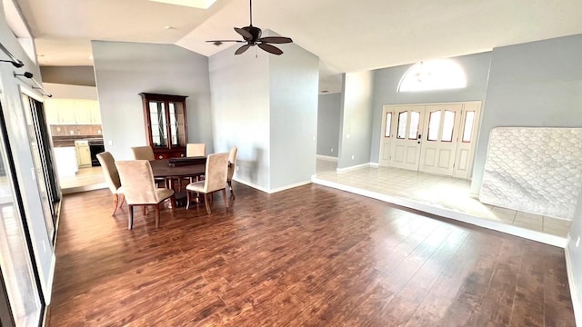 unfurnished dining area with dark wood-type flooring, ceiling fan, and high vaulted ceiling