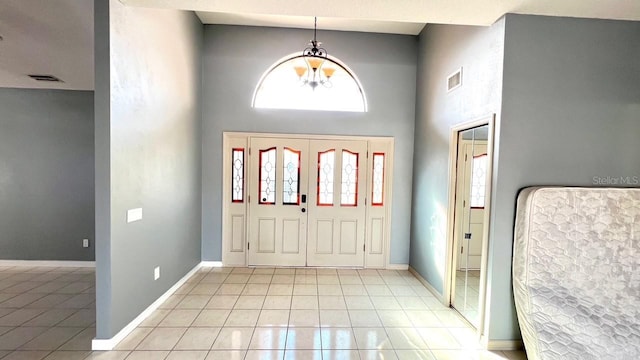 tiled foyer entrance featuring a chandelier and a high ceiling