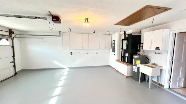 garage featuring heating unit, water heater, sink, electric panel, and a garage door opener