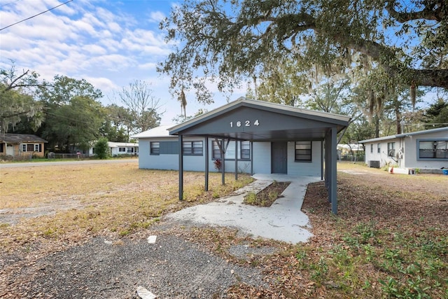 view of front of property featuring a carport, central AC unit, and a front lawn